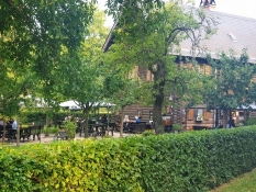 Das Restaurant in Alexandrowka ist in einem Holzhaus, von einem grünen Garten mit Betrieb umgeben